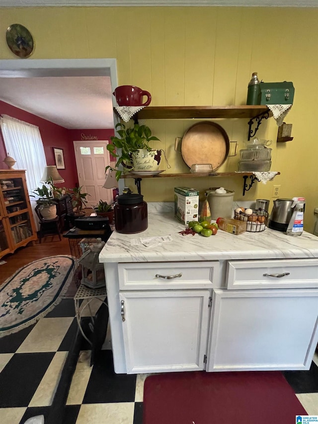 kitchen with wood walls, white cabinets, and light stone countertops