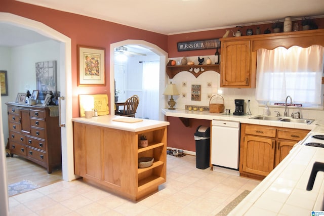 kitchen featuring light wood-type flooring, tile countertops, white dishwasher, sink, and ceiling fan