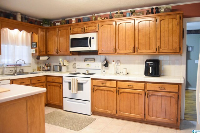 kitchen featuring white appliances, sink, tile counters, and tasteful backsplash