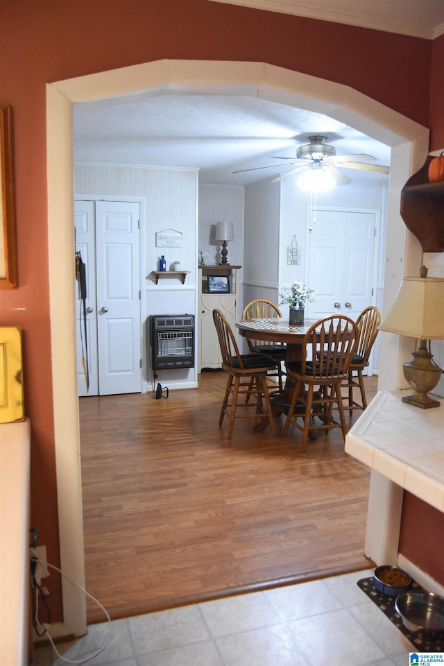 dining space with ceiling fan, crown molding, heating unit, and light hardwood / wood-style flooring