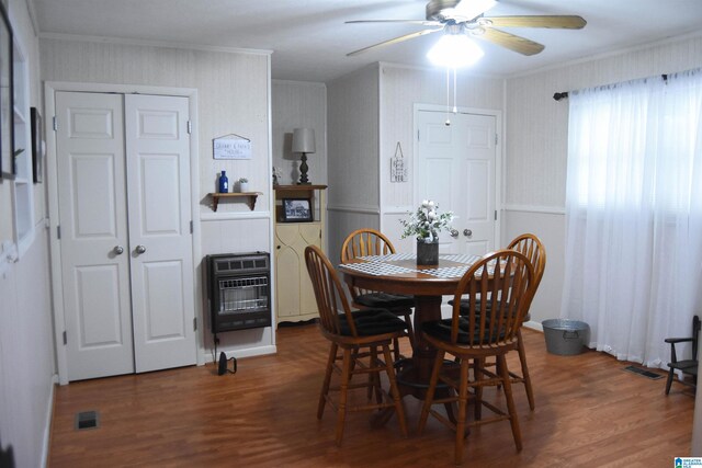 dining space with dark wood-type flooring, ceiling fan, crown molding, and heating unit