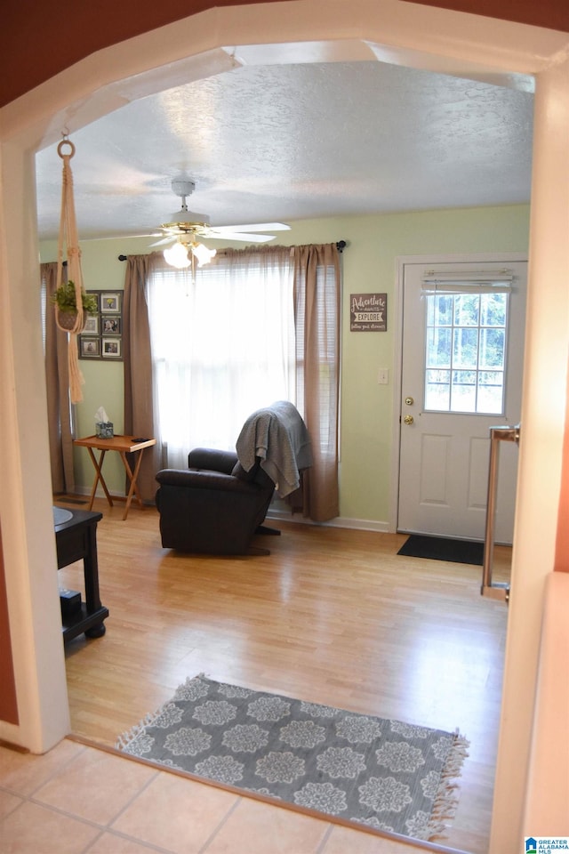 living room featuring a textured ceiling, ceiling fan, and light hardwood / wood-style floors