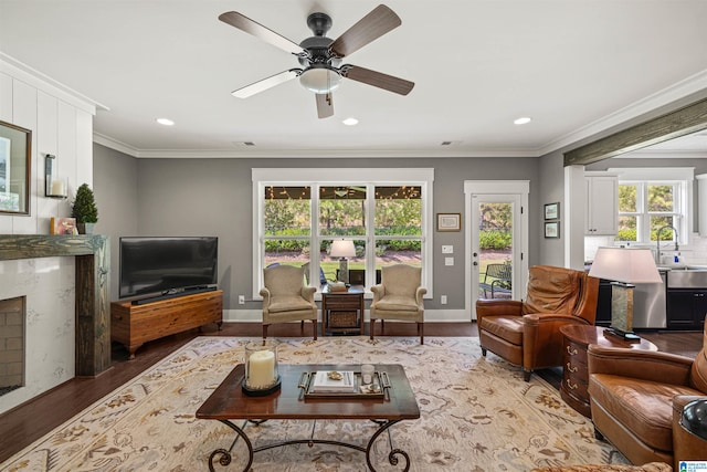 living room with hardwood / wood-style floors, ceiling fan, sink, and ornamental molding