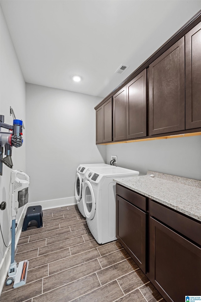 laundry area featuring cabinets, dark hardwood / wood-style floors, and washer and clothes dryer