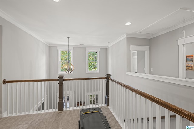 corridor featuring carpet flooring, crown molding, and an inviting chandelier