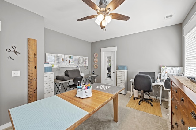 carpeted home office featuring ceiling fan