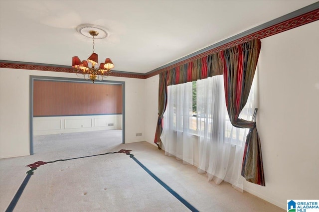 unfurnished dining area with light carpet, ornamental molding, and a chandelier