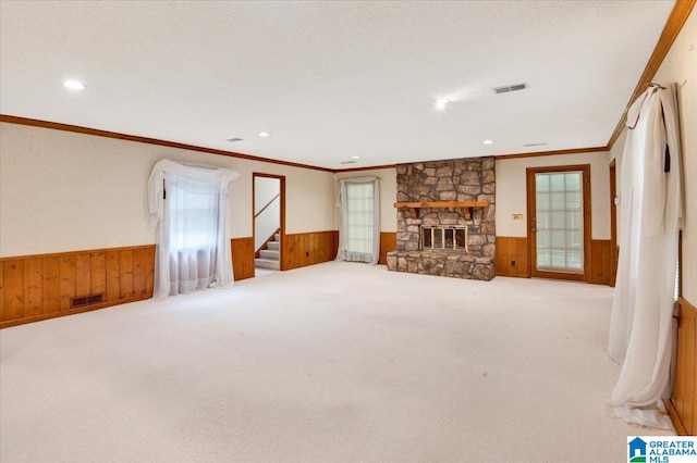 carpeted living room with a textured ceiling, a stone fireplace, and wooden walls