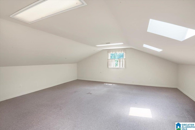 additional living space with vaulted ceiling with skylight and carpet floors