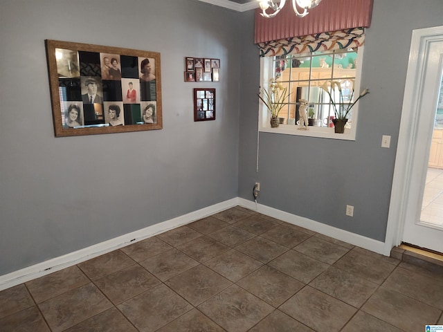 unfurnished dining area featuring crown molding, dark tile patterned flooring, and a notable chandelier