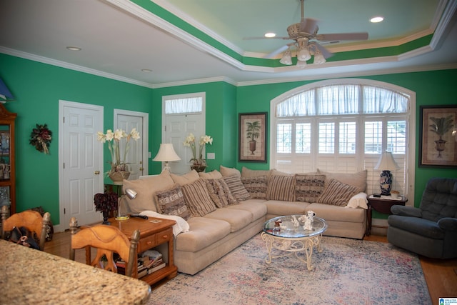 living room featuring crown molding, a raised ceiling, hardwood / wood-style flooring, and ceiling fan