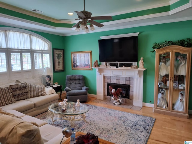 living room featuring a fireplace, ornamental molding, ceiling fan, and light hardwood / wood-style floors