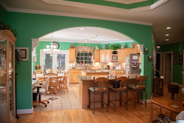 kitchen featuring hanging light fixtures, light brown cabinetry, ornamental molding, and a kitchen breakfast bar