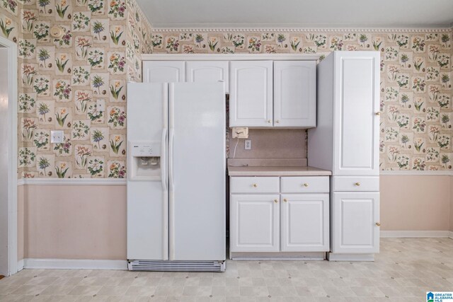 kitchen featuring white refrigerator with ice dispenser, crown molding, and white cabinetry