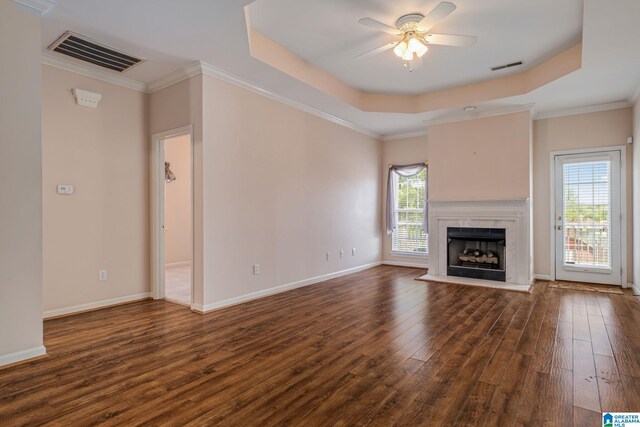 unfurnished living room featuring ceiling fan, a high end fireplace, dark hardwood / wood-style floors, and a tray ceiling