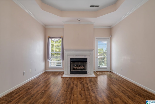 unfurnished living room with a tray ceiling, ornamental molding, dark hardwood / wood-style flooring, and a premium fireplace