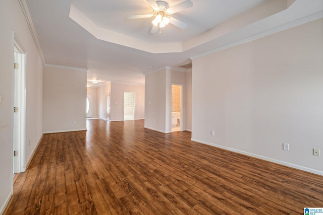 empty room featuring baseboards, dark wood finished floors, ornamental molding, a raised ceiling, and a ceiling fan