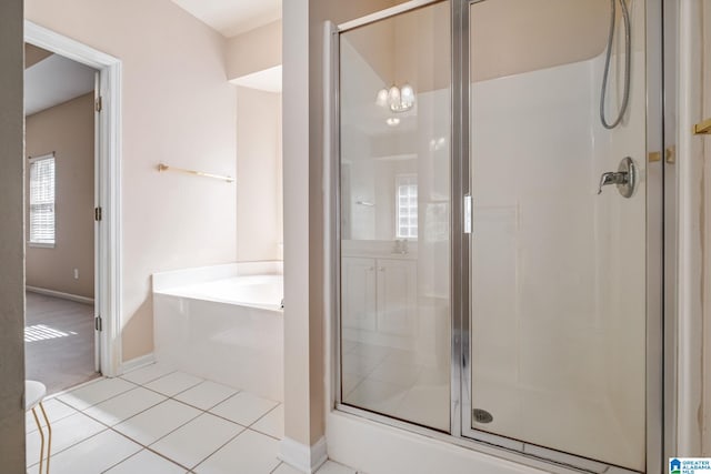 bathroom featuring tile patterned floors, a shower stall, baseboards, and a garden tub