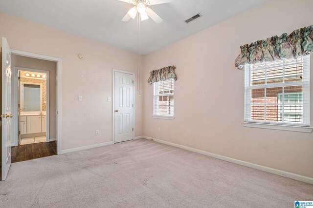 unfurnished bedroom featuring carpet, ceiling fan, and ensuite bathroom