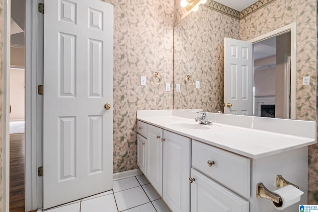 bathroom with wallpapered walls, tile patterned floors, vanity, and baseboards