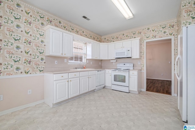 kitchen with visible vents, a sink, white appliances, wallpapered walls, and light countertops