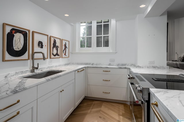 kitchen with high end stainless steel range, light stone counters, sink, light parquet floors, and white cabinets