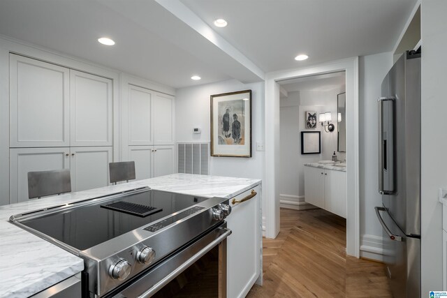 kitchen with stainless steel appliances, light stone counters, and white cabinetry