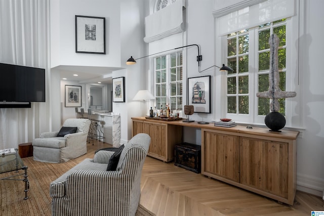 sitting room with a high ceiling and light parquet floors