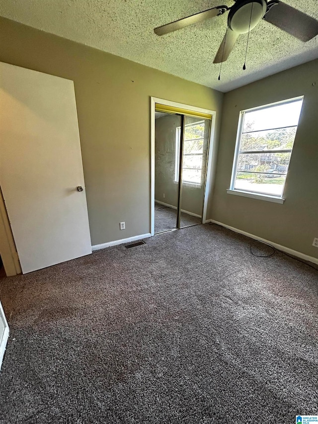 unfurnished bedroom featuring carpet floors, a closet, a textured ceiling, and baseboards