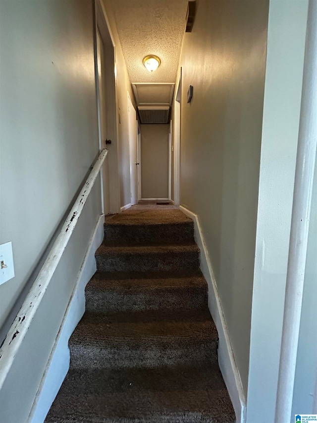 stairs featuring a textured ceiling and baseboards