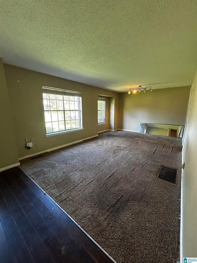 empty room with baseboards, visible vents, and a textured ceiling