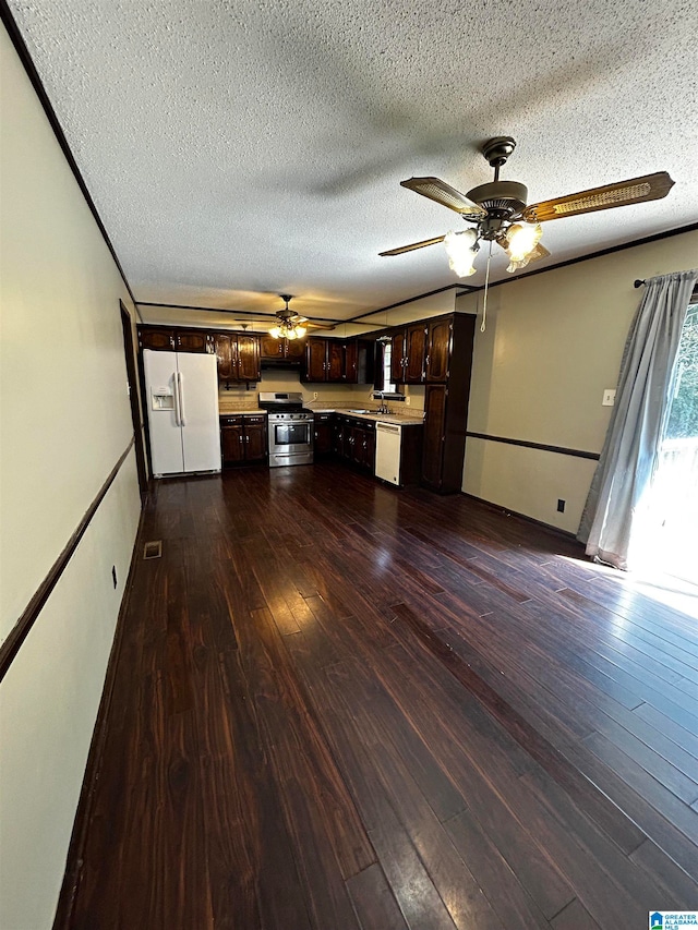 kitchen featuring dark brown cabinetry, white appliances, dark wood-style floors, light countertops, and a sink