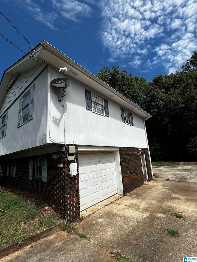 view of home's exterior featuring a garage, brick siding, and driveway