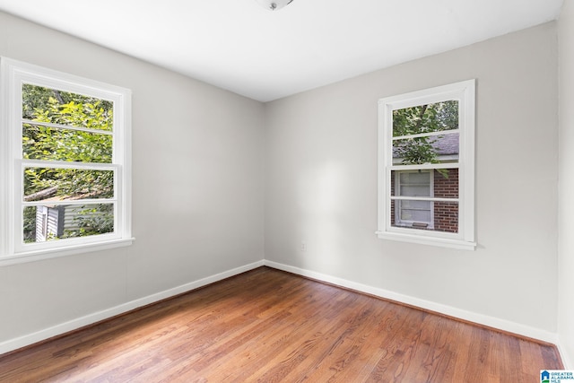 spare room with baseboards and wood finished floors