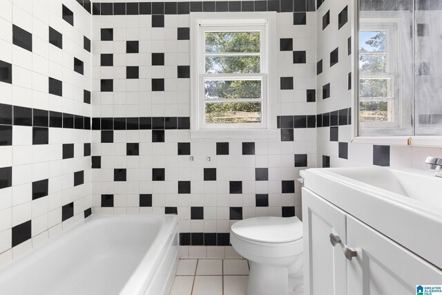 bathroom with vanity, a bathing tub, tile walls, toilet, and tile patterned floors