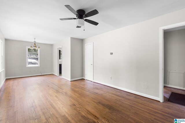 unfurnished living room featuring baseboards, wood finished floors, and ceiling fan with notable chandelier