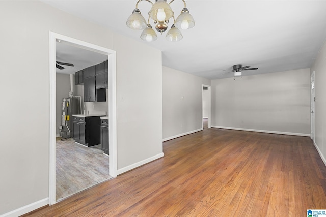 unfurnished room featuring water heater, baseboards, and wood finished floors