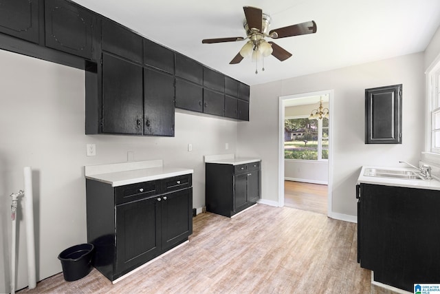 kitchen with dark cabinets, light countertops, light wood-style flooring, and baseboards