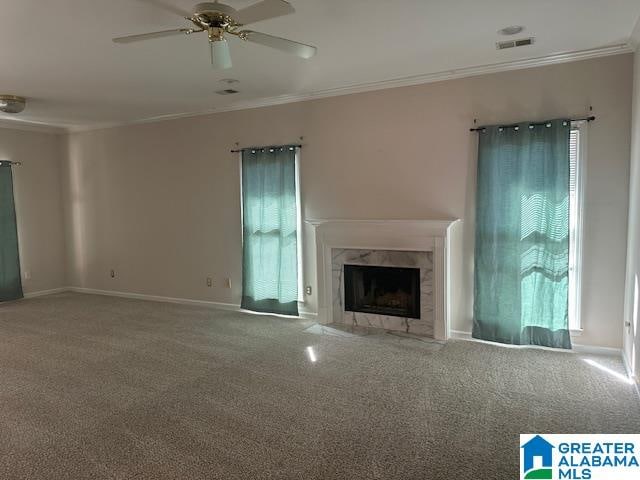 unfurnished living room featuring crown molding, a high end fireplace, carpet floors, and ceiling fan