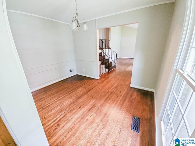 unfurnished room featuring a notable chandelier, hardwood / wood-style flooring, and crown molding