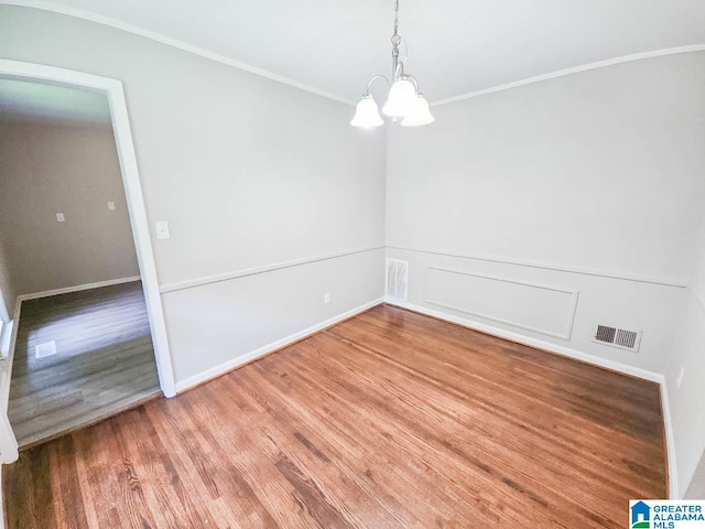 unfurnished dining area featuring wood-type flooring, an inviting chandelier, and ornamental molding