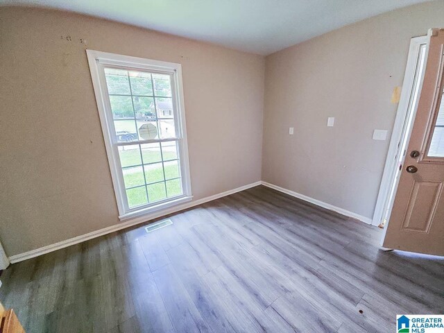 empty room with hardwood / wood-style flooring and a healthy amount of sunlight