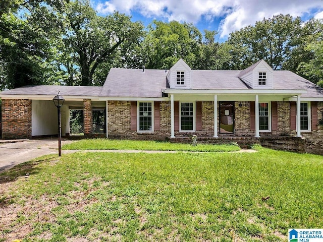 cape cod house with covered porch, a front yard, an attached carport, and brick siding