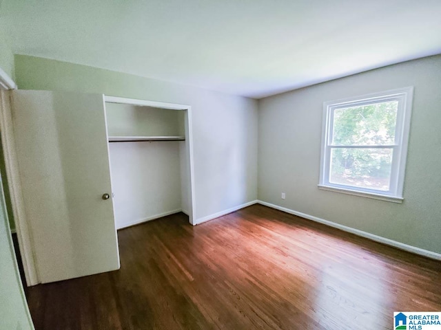 unfurnished bedroom with a closet and dark hardwood / wood-style floors