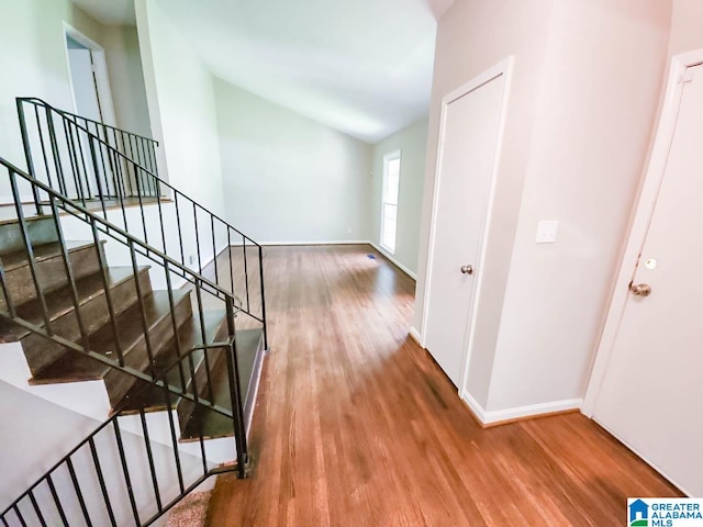 corridor with light hardwood / wood-style flooring and vaulted ceiling