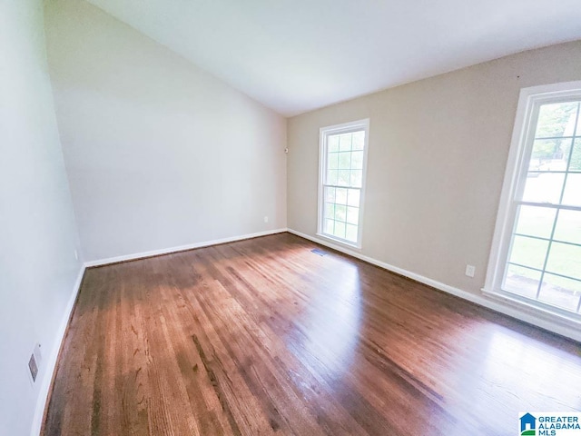 empty room featuring vaulted ceiling and dark hardwood / wood-style floors