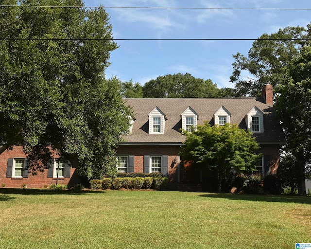 cape cod house with brick siding, roof with shingles, and a front yard