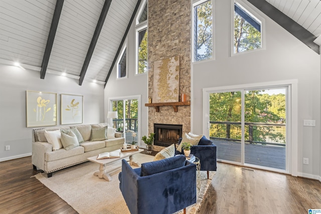 living room featuring high vaulted ceiling, baseboards, beam ceiling, a stone fireplace, and wood finished floors