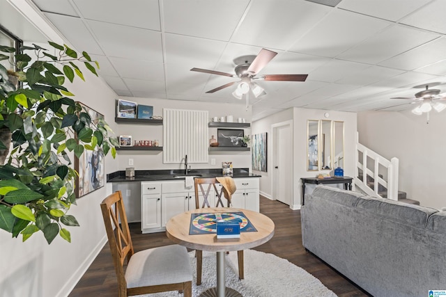 living room with ceiling fan, dark hardwood / wood-style floors, a drop ceiling, and sink