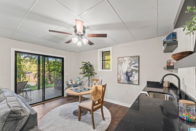 dining space with dark hardwood / wood-style flooring, a paneled ceiling, sink, and ceiling fan